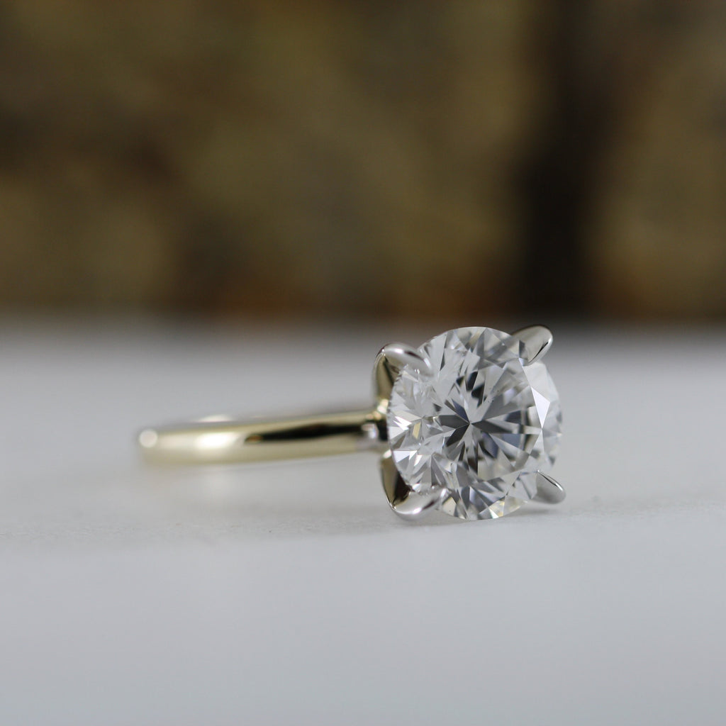 This stunning engagement ring features brilliant 4 carat round lab grown diamond set in white gold setting, beautifully complemented by a yellow gold shank. Two tone design enhances the diamond brightness creating outstanding 