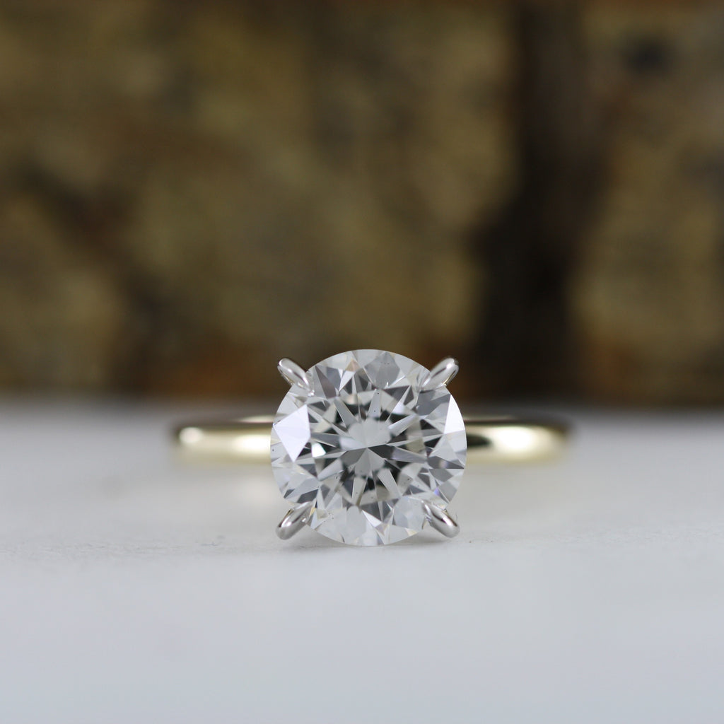 This stunning engagement ring features brilliant 4 carat round lab grown diamond set in white gold setting, beautifully complemented by a yellow gold shank. Two tone design enhances the diamond brightness creating outstanding appear.