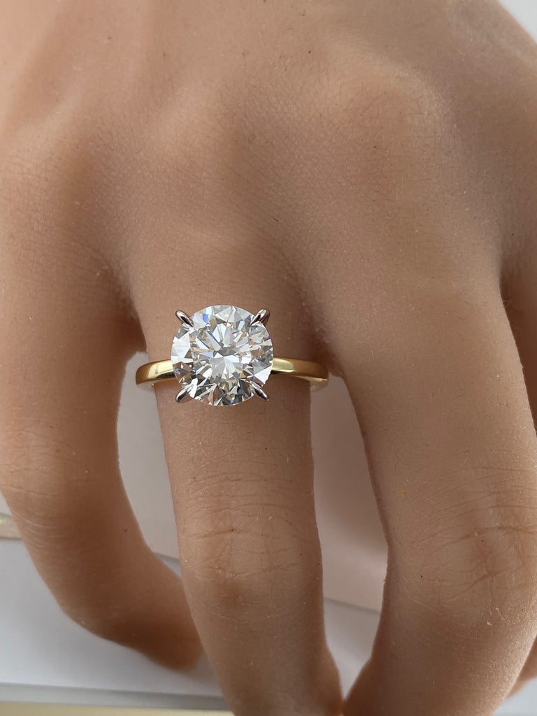 This stunning engagement ring features brilliant 4 carat round lab grown diamond set in white gold setting, beautifully complemented by a yellow gold shank. Two tone design enhances the diamond brightness creating outstanding appear.