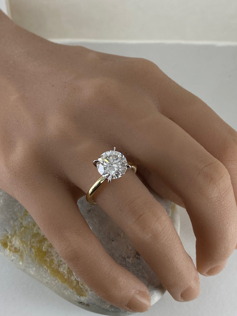 This stunning engagement ring features brilliant 4 carat round lab grown diamond set in white gold setting, beautifully complemented by a yellow gold shank. Two tone design enhances the diamond brightness creating outstanding appear.