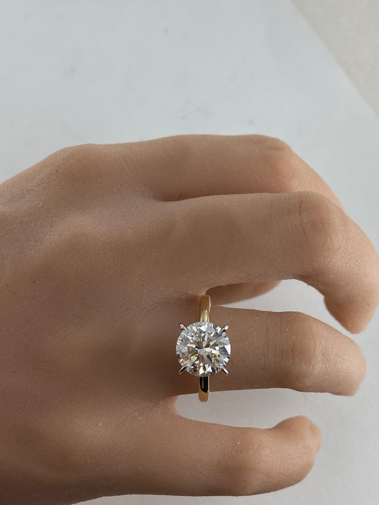 This stunning engagement ring features brilliant 4 carat round lab grown diamond set in white gold setting, beautifully complemented by a yellow gold shank. Two tone design enhances the diamond brightness creating outstanding appear.